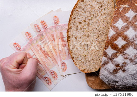 Clenched fist next to 5000 Russian Ruble banknotes and sliced bread. Concept of inflation and rising food prices 137511996