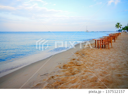 Dining on sand beach. People swim in ocean shoreon. Sea resort beach. Table, chair on in restaurant. 137512157