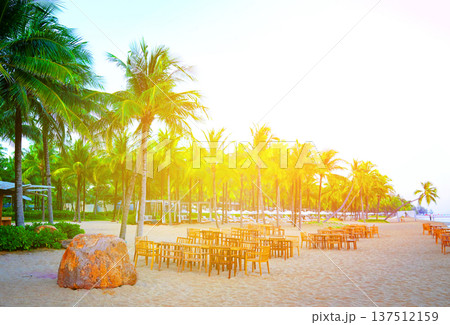 Dining on beach. People swim in ocean shore. Sea resort beach. Table, chair on sand in restaurant 137512159