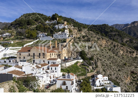 Exploring Frigiliana, Spain, with white houses on a hillside under a blue sky and mountains in the background in a sunny afternoon Exploring Frigiliana, Spain, with white houses on a hillside under a blue sky and mountains in the background in a sunny afternoon 137512225
