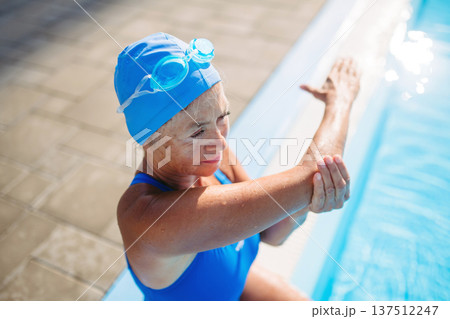 Older female swimmer stretching before swim in pool. Older female swimmer stretching before swim in pool. 137512247