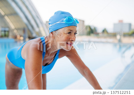 Older female swimmer stretching before swim in pool. 137512251