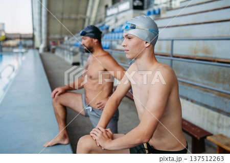 Father and teenage son preparing for swim training, stretching. 137512263