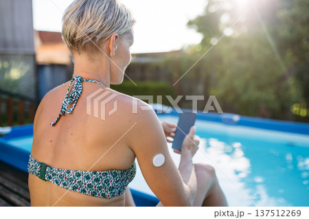 Woman using smartphone with wearable health sensor on arm. Woman using smartphone with wearable health sensor on arm. 137512269