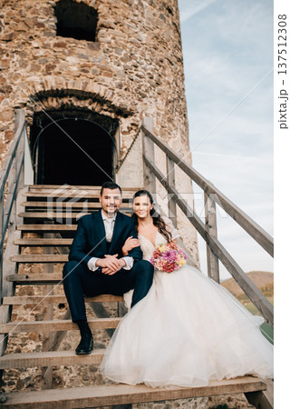 Portrait of beautiful wedding couple, sitting on wooden stairs. Portrait of beautiful wedding couple, sitting on wooden stairs. 137512308