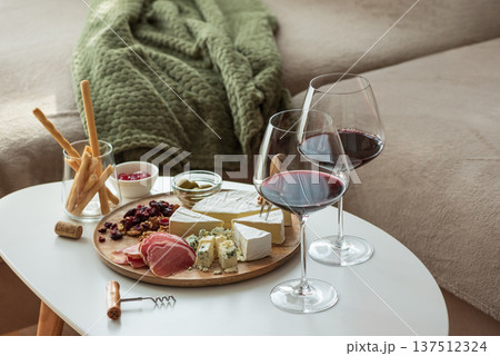 Cozy living room with two glasses of red wine and cheese on table Cozy living room with two glasses of red wine and cheese on table 137512324