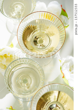 Champagne Glasses with White Peonies. Birthday or Wedding Celebration Arrangement. Top view Champagne Glasses with White Peonies. Birthday or Wedding Celebration Arrangement. Top view 137512333