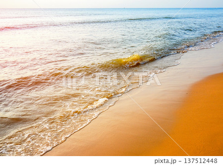 Tranquil seascape on sunset background. Soft sandy shore with warm. Waves at shoreline. Tranquil seascape on sunset background. Soft sandy shore with warm. Waves at shoreline. 137512448