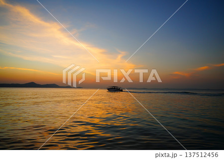 Boat moves sea on sunset near coastline in tropical island. Boat travels in ocean under sunset. Boat moves sea on sunset near coastline in tropical island. Boat travels in ocean under sunset. 137512456