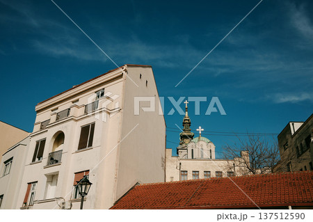 Historic residential houses with church tower rising above red rooftops. Traditional skyline scene under clear blue sky in Belgrade Historic residential houses with church tower rising above red rooftops. Traditional skyline scene under clear blue sky in Belgrade 137512590