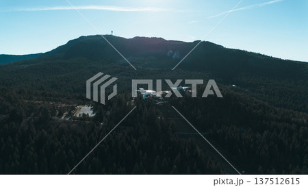 Aerial view of Sarajevo cable car station surrounded by dense pine forest and mountain ridges. Modern infrastructure blends with nature, showing urban connection to wilderness and tourism development Aerial view of Sarajevo cable car station surrounded by dense pine forest and mountain ridges. Modern infrastructure blends with nature, showing urban connection to wilderness and tourism development 137512615