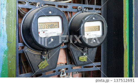 Two old black electricity meters in an electrical panel. They display electricity consumption Two old black electricity meters in an electrical panel. They display electricity consumption 137512691