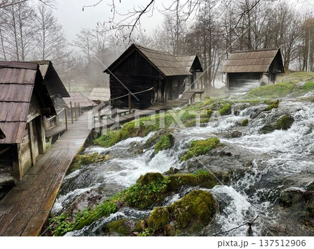 Traditional wooden water mills in Jajce, Bosnia, surrounded by flowing streams and mossy rocks, creating a scenic rural landscape with heritage and nature harmony 137512906