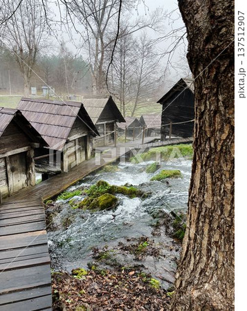 Traditional wooden water mills in Jajce, Bosnia, surrounded by flowing streams and mossy rocks, creating a scenic rural landscape with heritage and nature harmony Traditional wooden water mills in Jajce, Bosnia, surrounded by flowing streams and mossy rocks, creating a scenic rural landscape with heritage and nature harmony 137512907