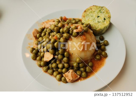 Mashed potatoes topped with green pea stew and chicken pieces on a white plate. Simple comfort food dish, homemade lunch concept with vegetables and protein 137512952
