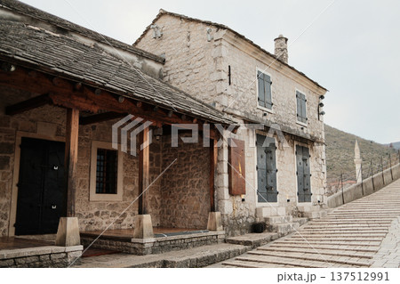 Stone house near the Old Bridge in Mostar with wooden porch and historic pavement. Traditional Balkan architecture showing preserved heritage and old town atmosphere 137512991