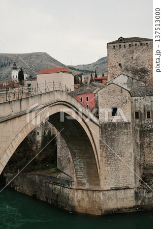 Close view of the historic stone bridge in Mostar with old town buildings and river below. Iconic Balkan architecture showing medieval heritage and cultural identity Close view of the historic stone bridge in Mostar with old town buildings and river below. Iconic Balkan architecture showing medieval heritage and cultural identity 137513000