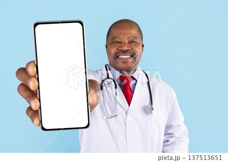Mature african american doctor holding smartphone toward camera with blank display 137513651