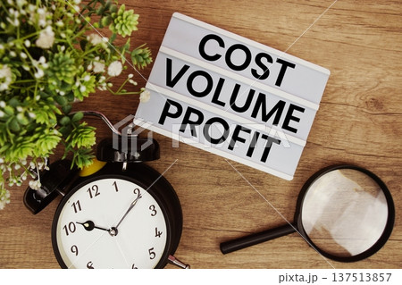 Cost Volume Profit text in lightbox with magnifying glass and alarm clock flat lay on wooden background 137513857