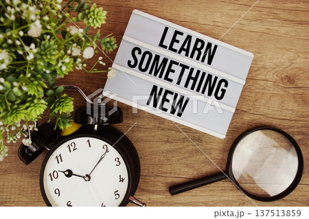 Learn Something New text in lightbox with magnifying glass and alarm clock flat lay on wooden background Learn Something New text in lightbox with magnifying glass and alarm clock flat lay on wooden background 137513859
