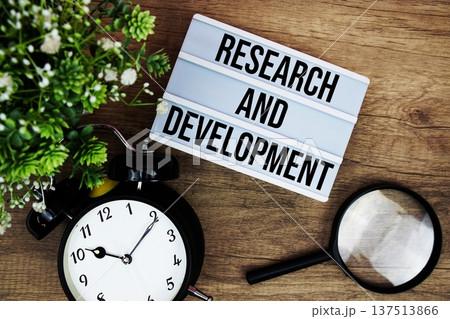 Research And Development text in lightbox with magnifying glass and alarm clock flat lay on wooden background Research And Development text in lightbox with magnifying glass and alarm clock flat lay on wooden background 137513866