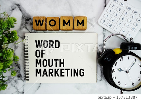 WOMM Word Of Mouth Marketing text with calculator and alarm clock on marble background WOMM Word Of Mouth Marketing text with calculator and alarm clock on marble background 137513887