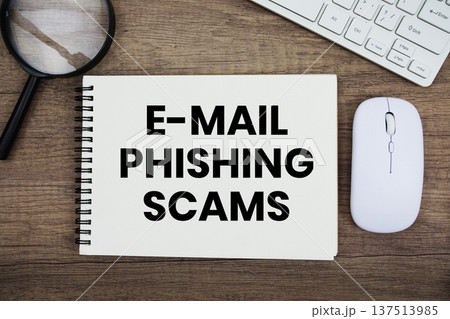 E-Mail Phishing Scams text written on notepad with keyboard, optical mouse and magnifying glass on wooden background; E-Mail Phishing Scams text written on notepad with keyboard, optical mouse and magnifying glass on wooden background; 137513985