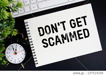 Don't Get Scammed text written on notepad with keyboard and alarm clock on black background Don't Get Scammed text written on notepad with keyboard and alarm clock on black background 137514193