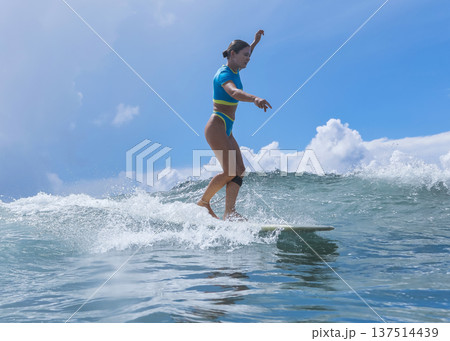 Relaxed Woman Balances On Surfboard Beneath Cloudy Sky During Ocean Swells Relaxed Woman Balances On Surfboard Beneath Cloudy Sky During Ocean Swells 137514439