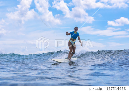 Woman Standing Proudly On Surfboard Amidst Turbulent Cloudy Backdrop Woman Standing Proudly On Surfboard Amidst Turbulent Cloudy Backdrop 137514458