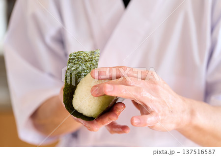 おにぎりに海苔を巻く料理人 137516587