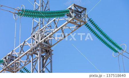 Close-up view of suspended glass insulators on high-voltage lines at a transformer substation, without people, at daytime, on background of blue sky 137518640