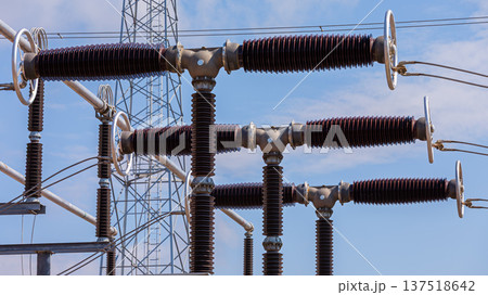 Close up view of various elements and high-voltage insulators of a transformer substation, without people, at daytime on background of blue sky 137518642