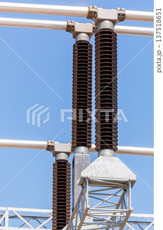 Vertical view of various elements and high-voltage insulators of a transformer substation, without people, at daytime on background of blue sky Vertical view of various elements and high-voltage insulators of a transformer substation, without people, at daytime on background of blue sky 137518651