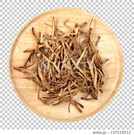 Top view of dried lily buds on a round wooden plate isolated. Traditional Chinese golden needle lily flowers used as a healthy culinary ingredient or herbal medicine. 137519512