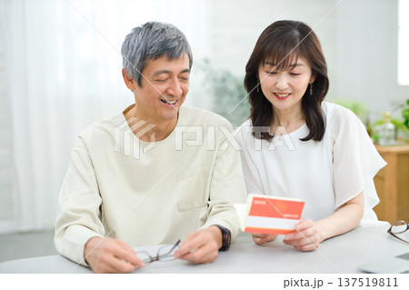 リビングで貯金通帳を見る60代の夫婦 137519811