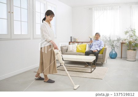 会話をしながら掃除機をかける笑顔の女性と60代の男性 137519812