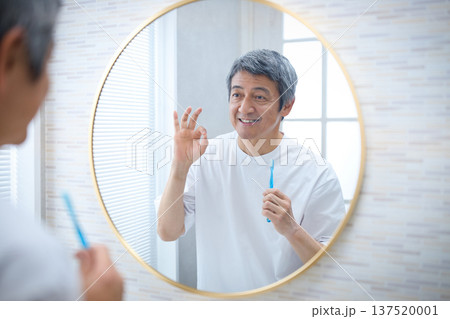 鏡を見ながら歯ブラシを持つ笑顔の60代の男性 鏡を見ながら歯ブラシを持つ笑顔の60代の男性 137520001