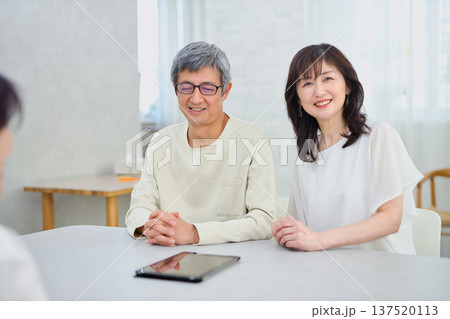 夫婦にタブレットで説明をする営業の女性 夫婦にタブレットで説明をする営業の女性 137520113