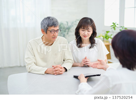 夫婦にタブレットで説明をする営業の女性 夫婦にタブレットで説明をする営業の女性 137520254