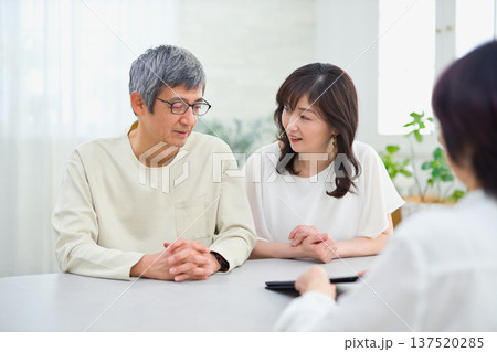 夫婦にタブレットで説明をする営業の女性 137520285