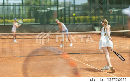 Concentrated sporty girl with tennis racquet and ball in her hands standing and ready to play match standing Concentrated sporty girl with tennis racquet and ball in her hands standing and ready to play match standing 137520951