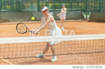 Female athlete plays tennis on open court Female athlete plays tennis on open court 137521010