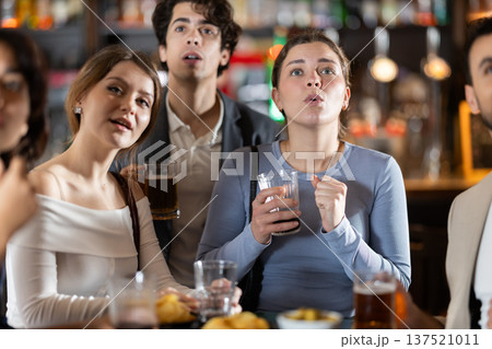 Group of emotional friends watch a sports match with interest in bar 137521011