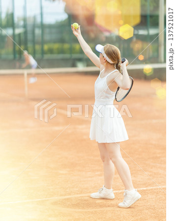 Woman playing tennis against female opponent on tennis court 137521017