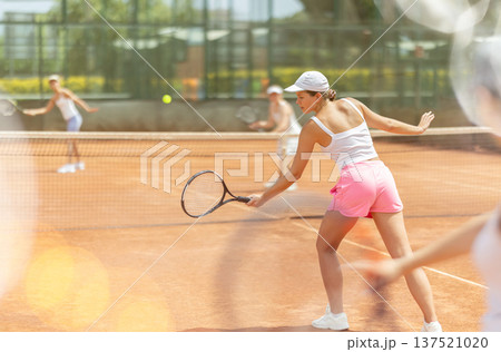 Female athlete plays tennis on open court Female athlete plays tennis on open court 137521020