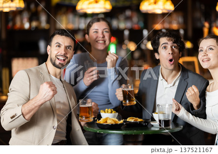 Happy friends celebrating victory of their favorite team while watching match in pub Happy friends celebrating victory of their favorite team while watching match in pub 137521167