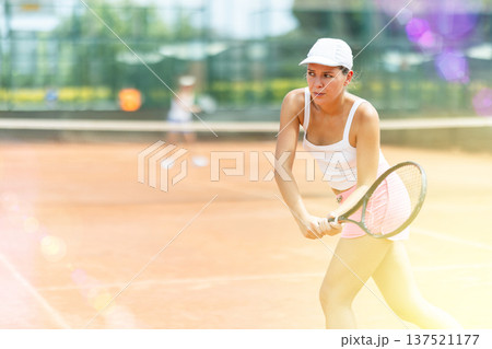 Female athlete plays tennis on open court Female athlete plays tennis on open court 137521177