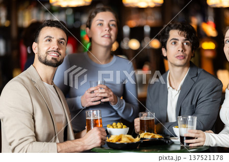 group of friends watching a game in a sports bar group of friends watching a game in a sports bar 137521178