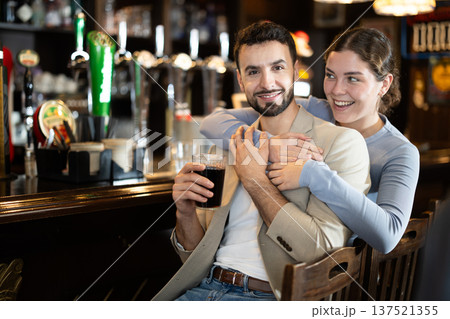 Young couple with mugs of beer in their hands chatting near the bar in nightclub 137521355